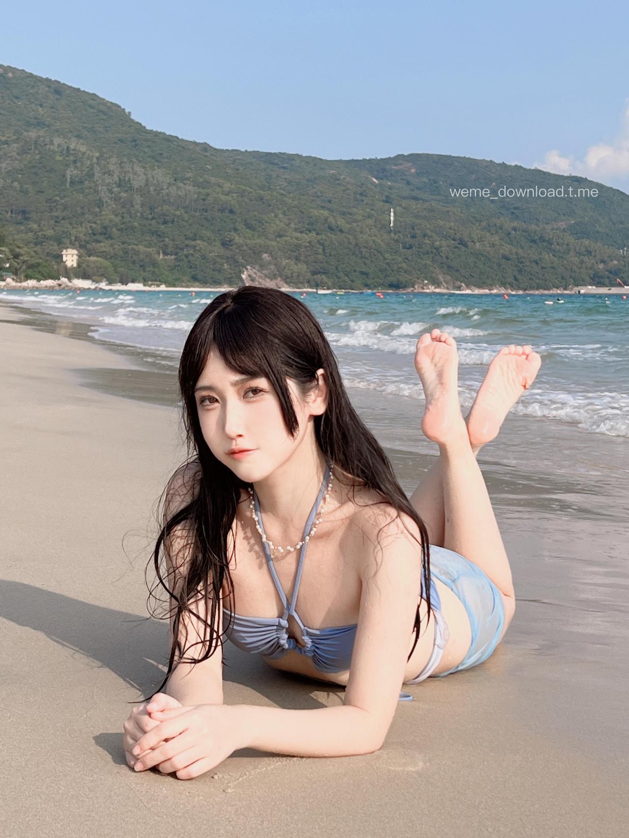 不呆猫穿浅蓝泳装伏在沙滩上并望向镜头