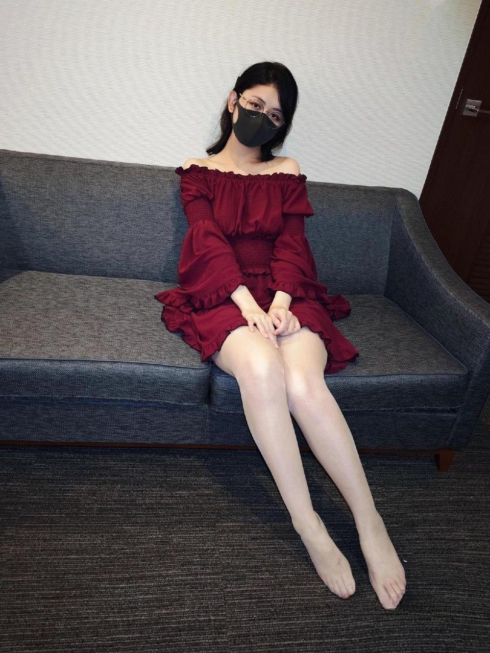Naimi奶咪穿酒红露肩长袖衣装坐在灰色沙发上