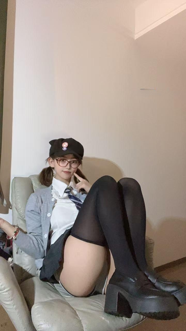 吞吞戴黑帽与眼镜穿灰色开衫坐在浅色扶手椅上