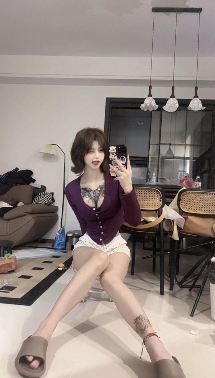 吞吞穿紫色开衫与浅色短裤坐在室内持手机