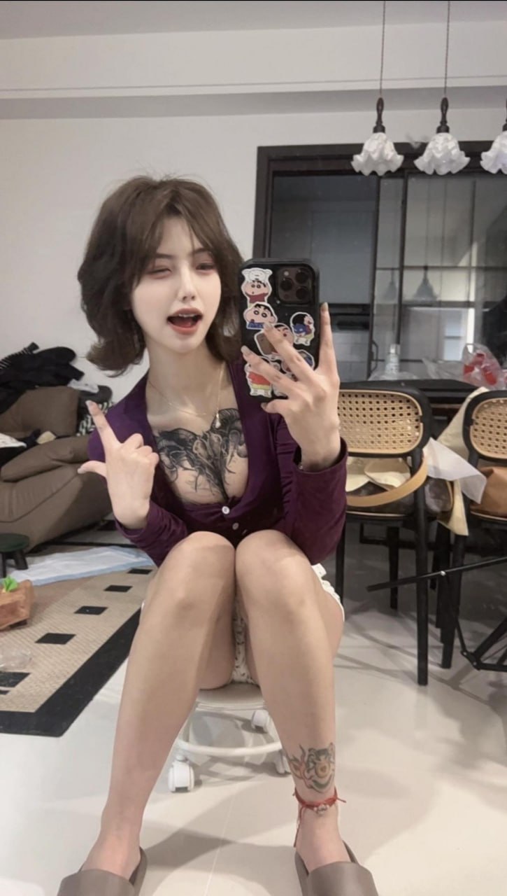 吞吞穿紫色纽扣开衫在餐椅前举手持手机镜照