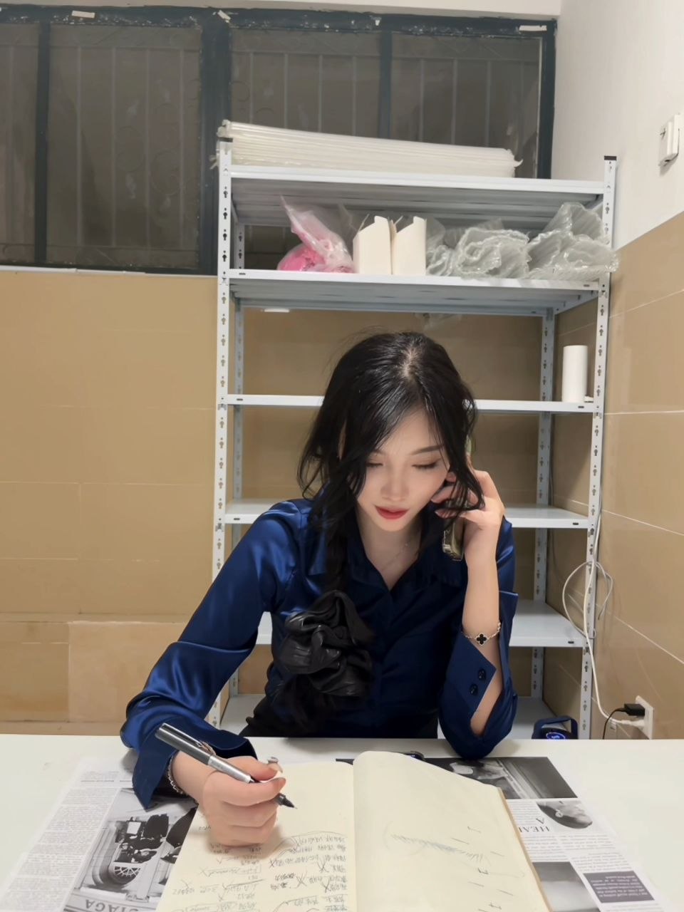 杨晨晨穿蓝色衬衣在金属置物架前接电话并用笔写字 杨晨晨穿蓝色衬衣在金属置物架前接电话并用笔写字