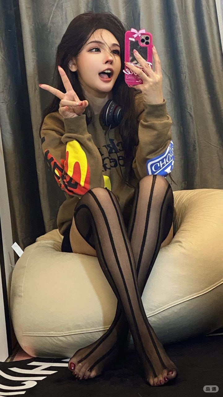 于芷晴穿棕色印花卫衣挂耳机坐在浅色椅上比手势